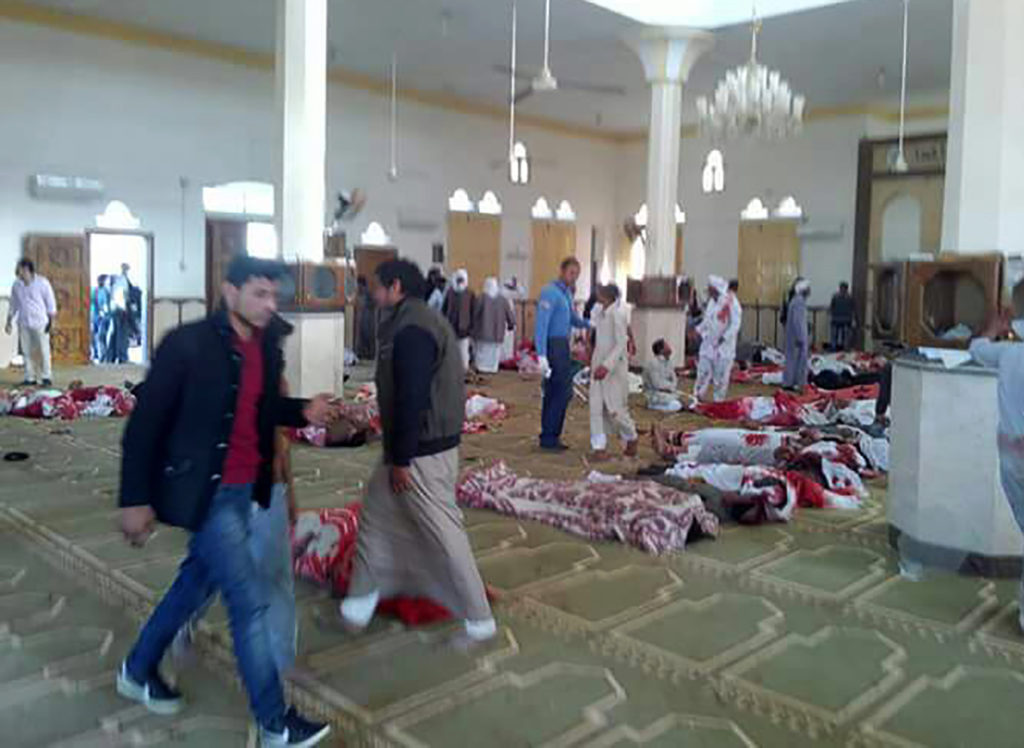 Egyptians walk past bodies following a gun and bombing attack at the al-Rawdah mosque in the Sinai Peninsula during Friday...