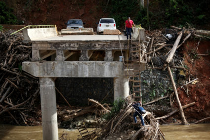 A woman looks as her husband climbs down a ladder at a partially destroyed bridge, after Hurricane Maria hit the area in September, in Utuado, Puerto Rico November 9, 2017. Picture taken November 9, 2017. REUTERS/Alvin Baez TPX IMAGES OF THE DAY - RC14D74F7730