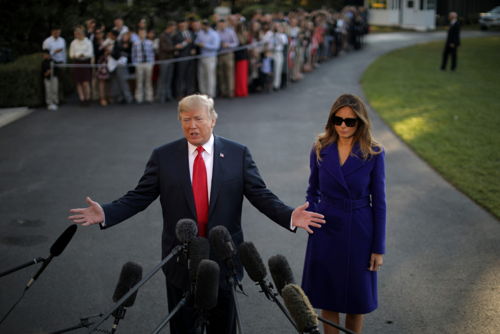 U.S. President Donald Trump talks with reporters accompanied by First Lady Melania Trump as they depart the White House fo...