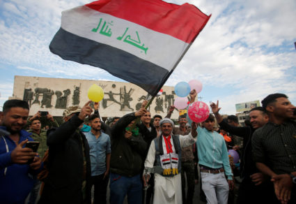 Iraqi people gather as they celebrate the final victory over the Islamic State at Tahrir Square in Baghdad