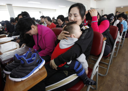 A North Korean defector (R) holds her son as she prays for human rights in North Korea during a service at Saetu Church in Seoul April 25, 2010. The North Korean Refugees' Church Coalition, consisting of eight Christian churches for North Korean defectors, held the first joint prayers for the remaining North Koreans on Sunday. REUTERS/Jo Yong-Hak (SOUTH KOREA - Tags: POLITICS RELIGION) - GM1E64P1BP701