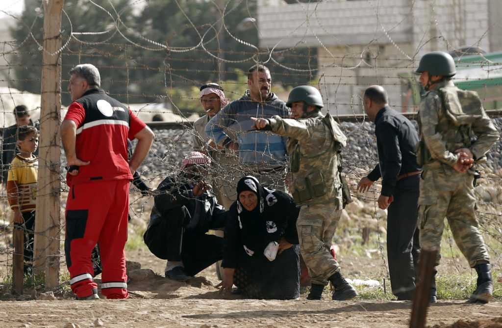 Residents from the northern Syrian town of Ras al-Ain cross a border fence into the Turkish town of Ceylanpinar to escape ...