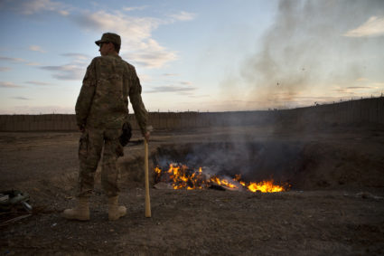 A U.S. Army soldier watches bottled water that had gone bad burn in a burn-pit at Forward Operating Base Azzizulah in Maiwand District, Kandahar Province, Afghanistan, February 4, 2013. REUTERS/Andrew Burton (AFGHANISTAN - Tags: MILITARY) - GM1E925034G01