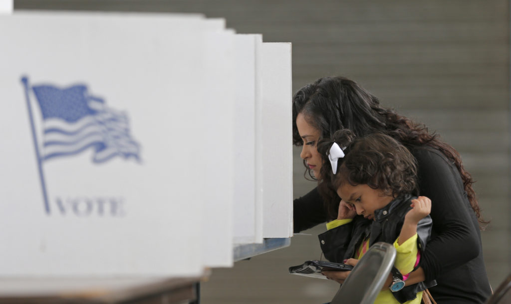 Betsy Argueta holds her daughter Isabella, 2, as she votes in the U.S. presidential election at the National Guard Armory ...