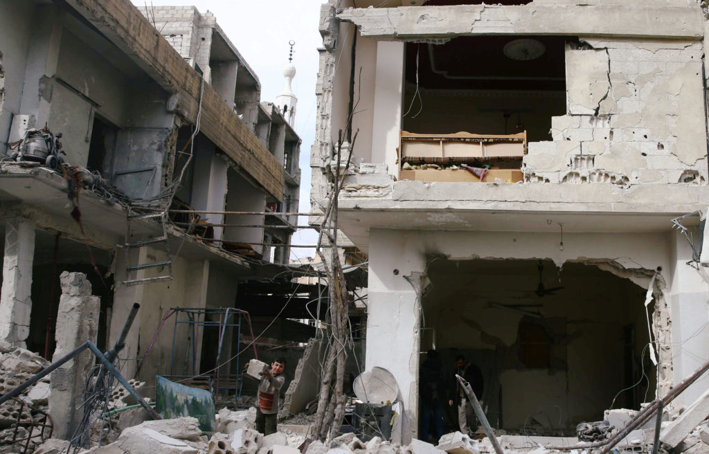 A child removes debris from a damage building in the besieged town of Douma, Eastern Ghouta, Damascus, Syria on Feb. 25. P...