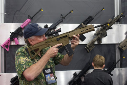 A man takes aim with an assault rifle at an exhibit booth at the George R. Brown convention center, the site for the National Rifle Association's (NRA) annual meeting in Houston, Texas May 5, 2013. REUTERS/Adrees Latif