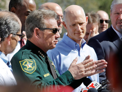 Broward County Sheriff Scott Israel speaks to the media while Florida Governor Rick Scott listens outside Marjory Stoneman Douglas High School one day after a shooting at the school left 17 dead, in Parkland, Florida, U.S., February 15, 2018. REUTERS/Jonathan Drake - RC1AB3EA6CF0