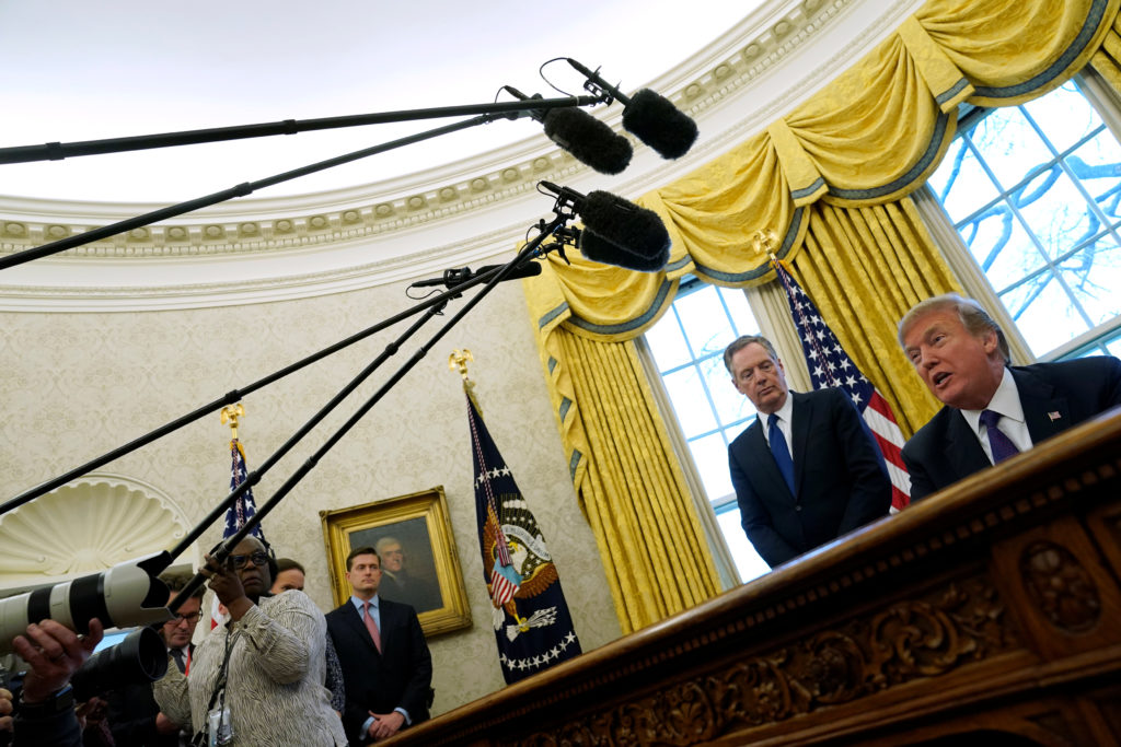 Trade Representative Robert Lighthizer stands behind President Donald Trump as Trump prepares to sign directives to impose...