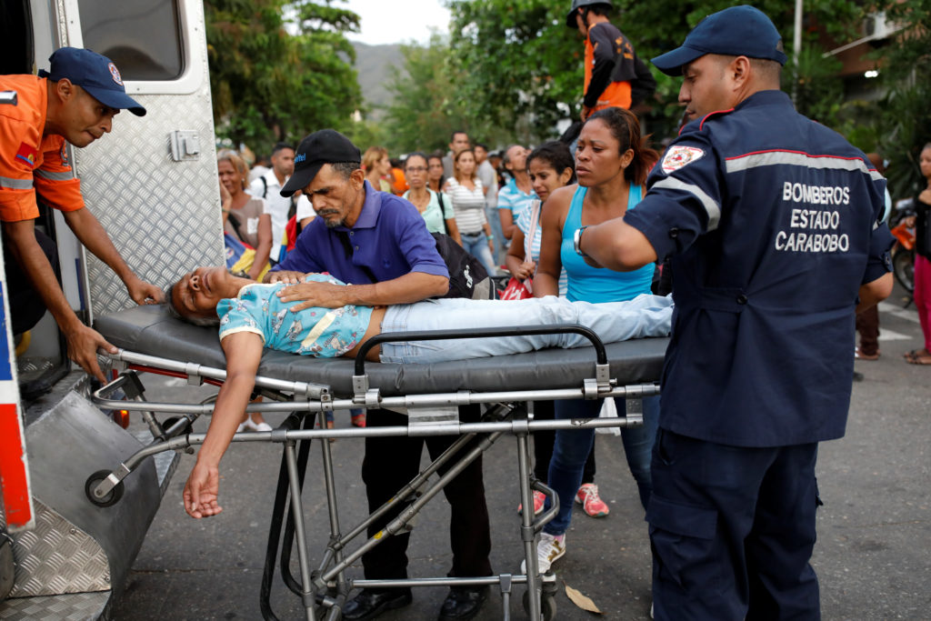 Paramedics help a relative of inmates held at the General Command of the Carabobo Police, who fainted, outside the prison, where a fire occurred in the cells area, according to local media, in Valencia, Venezuela March 28, 2018. REUTERS/Carlos Garcia Rawlins