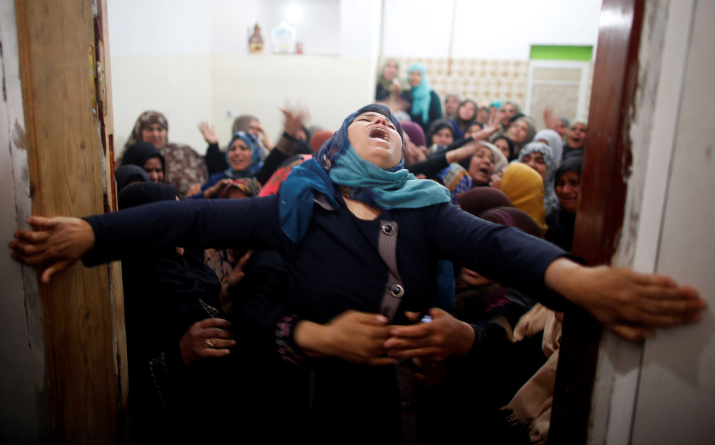Mourners hold back a relative of Palestinian Hamdan Abu Amshah, who was killed along Israel border with Gaza, during his f...