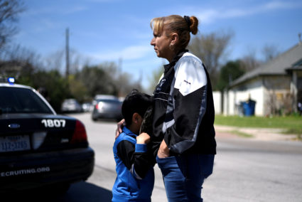 Isaac Machado hides behind his hat against his mother Delores just outside the scene of an explosion on Galindo Street in Austin, Texas, U.S., March 12, 2018. REUTERS/Sergio Flores - RC19E5318870
