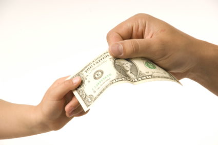close-up adult hand taking dollar bill from child's hand (Photo by: Digital Light Source/UIG via Getty Images)