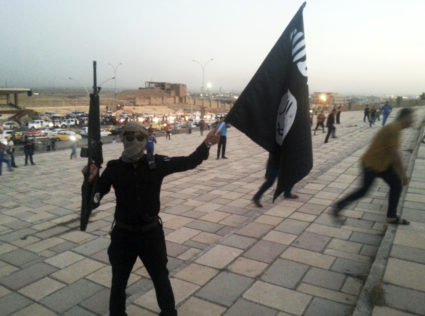 A fighter of the Islamic State of Iraq and the Levant (ISIL) holds an ISIL flag and a weapon on a street in the city of Mosul, June 23, 2014. U.S. Secretary of State John Kerry held crisis talks with leaders of Iraq's autonomous Kurdish region on Tuesday urging them to stand with Baghdad in the face of a Sunni insurgent onslaught that threatens to dismember the country. Picture taken June 23, 2014. REUTERS/Stringer (IRAQ - Tags: CIVIL UNREST POLITICS TPX IMAGES OF THE DAY) - GM1EA6P01IV01