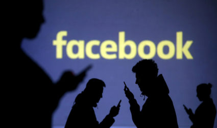 Silhouettes of mobile users are seen next to a screen projection of the Facebook logo in this picture illustration. File photo by Dado Ruvic/Illustration/Reuters