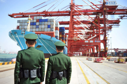 Police officers are seen in front of a cargo ship with containers at a port in Qingdao, Shandong province, China April 6, 2018. Photo by Reuters