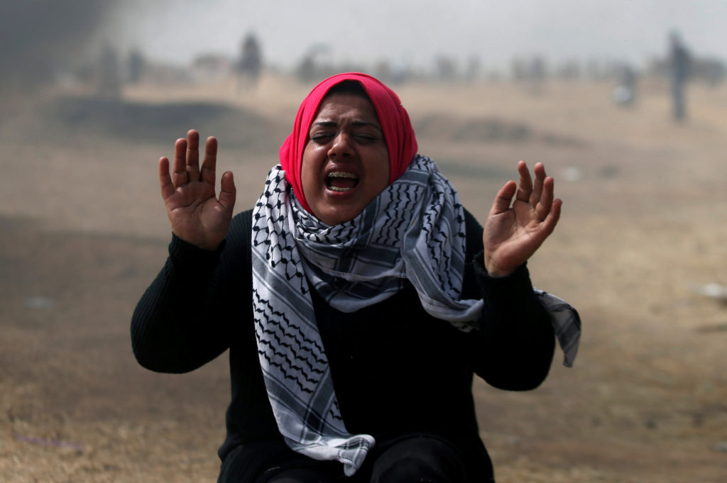 A woman demonstrator reacts to tear gas fired by Israeli troops during clashes at a protest at the Israel-Gaza border wher...