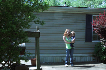 Casey Britton holds her younger son, Gavin, on the front porch of their home in Linden, Tennessee. Photo by Laura Santhanam/PBS NewsHour