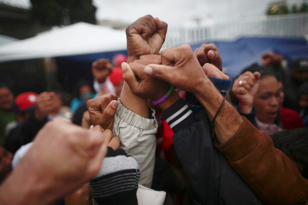 Members of a caravan of migrants from Central America, celebrate near the San Ysidro checkpoint as the first fellow migran...