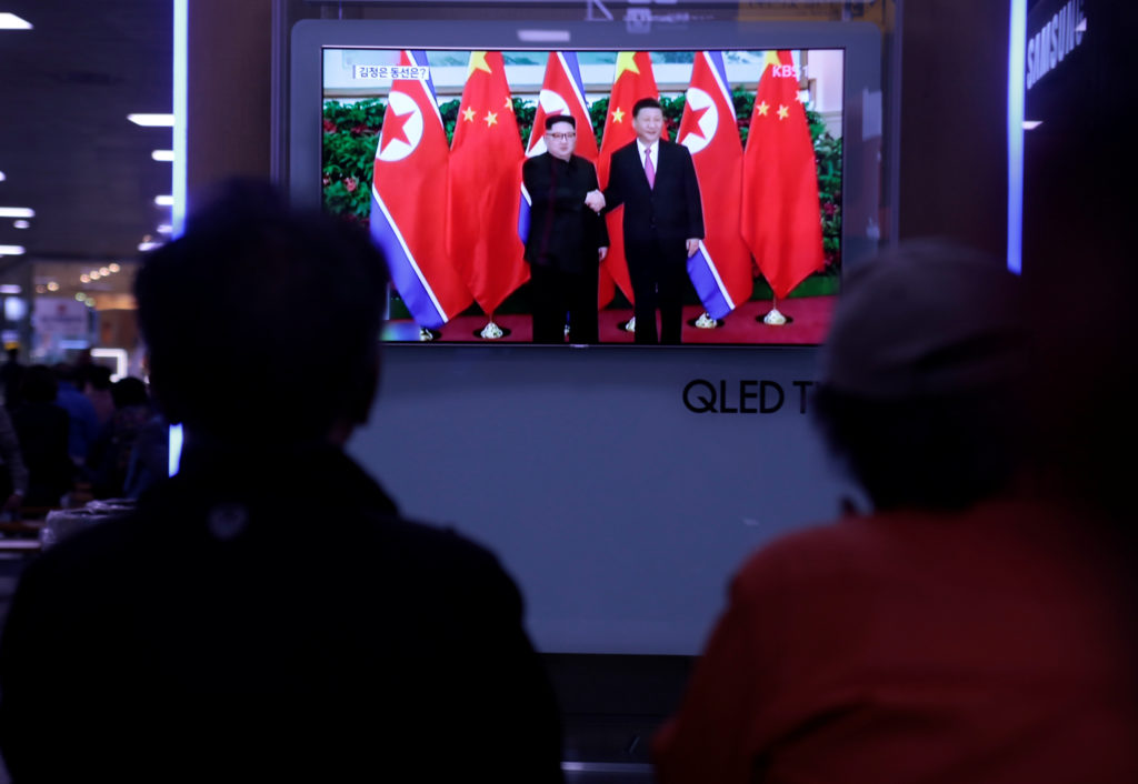 People watch a TV news report about the meeting between North Korean leader Kim Jong Un and Chinese President Xi Jinping a...
