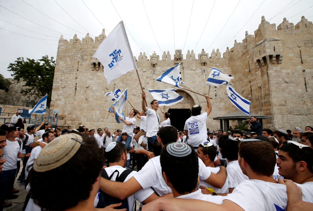 Israelis celebrate as they hold Israeli flags during a parade marking the annual Jerusalem Day, at Damascus Gate in Jerusa...