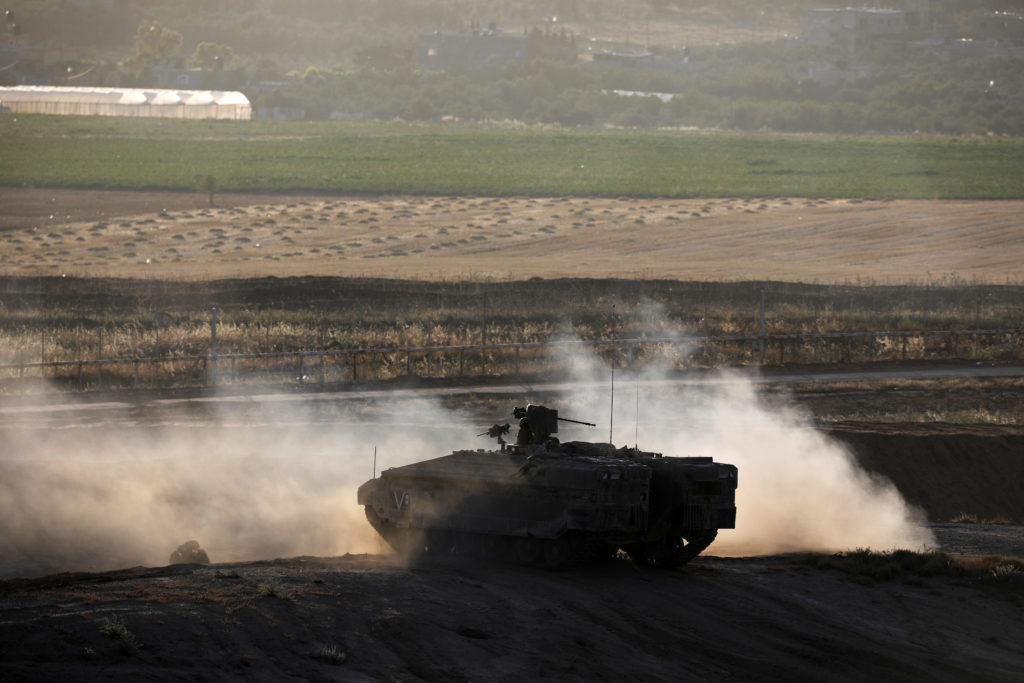 An Israeli armoured personnel carrier (APC) maneuvers on the Israeli side of the border fence between Israel and the Gaza ...