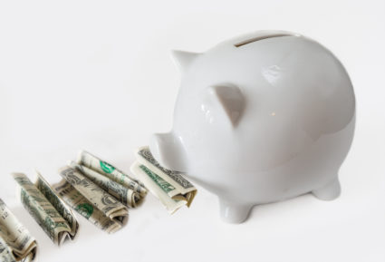 TORONTO, ONTARIO, CANADA - 2015/04/05: White piggy bank eating USA dollars one at a time, financial concept, saving one dollar at a time. Image over white background not isolated. (Photo by Roberto Machado Noa/LightRocket via Getty Images)