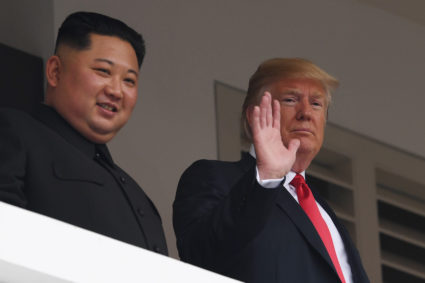 President Donald Trump (R) waves as he and North Korea's leader Kim Jong Un look on from a veranda during their historic U.S.-North Korea summit, at the Capella Hotel on Sentosa island in Singapore on June 12, 2018. Photo by Saul Loeb/AFP/Getty Images