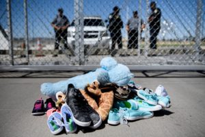 Security personnel stand before shoes and toys left at the Tornillo Port of Entry where minors crossing the border without proper papers have been housed after being separated from adults on June 21, 2018 in Tornillo, Texas. Photo by Brendan Smialowski/AFP/Getty Images