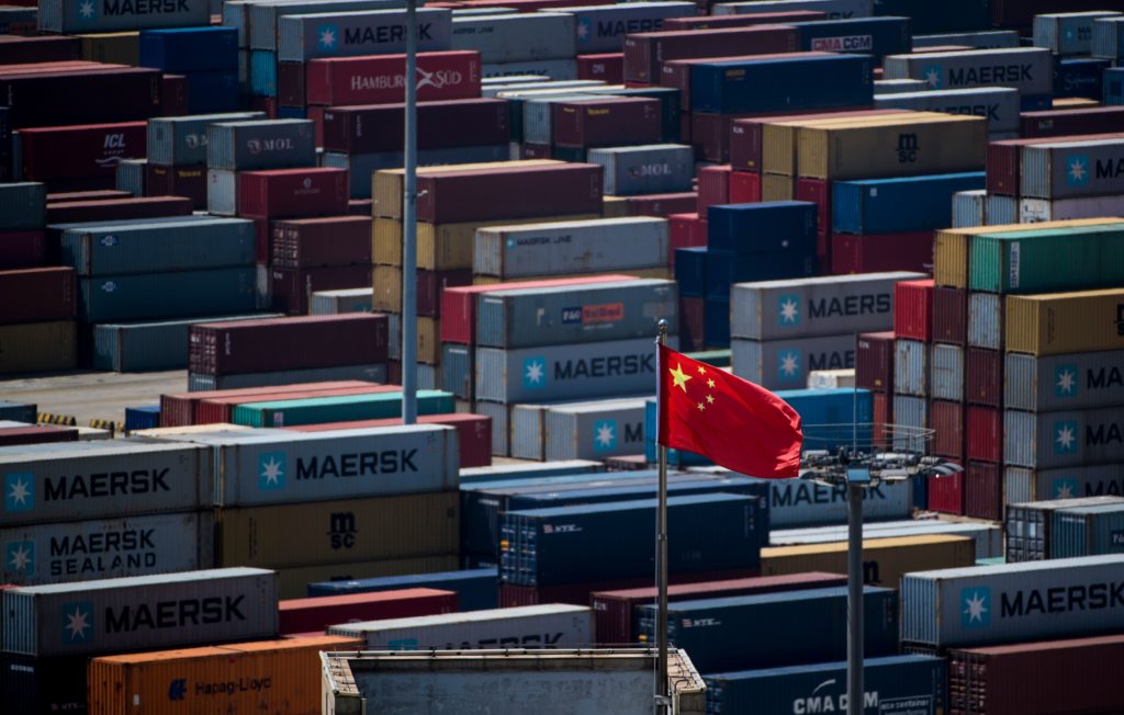 A Chinese flag is seen in front of containers at the Yangshan Deep-Water Port, an automated cargo wharf, in Shanghai. Phot...
