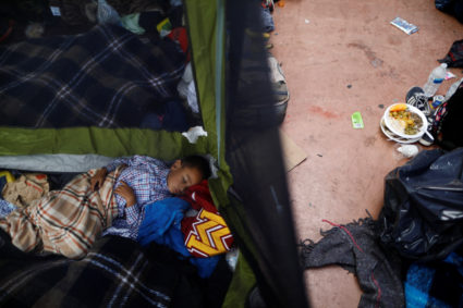 A child traveling with a caravan of migrants from Central America sleeps at a camp near the San Ysidro checkpoint, after U.S. border authorities allowed the first small group of women and children entry from Mexico overnight, in Tijuana, Mexico. Photo by Edgard Garrido/Reuters