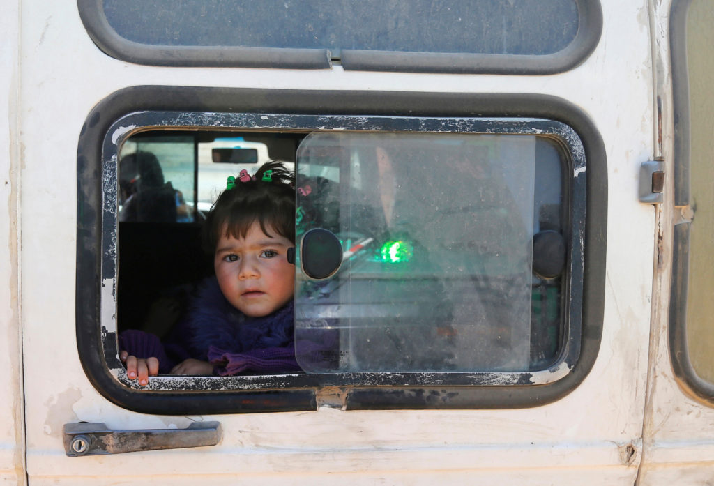 A child looks out of a window as Syrian refugees prepare to return to Syria from the Lebanese border town of Arsal, Lebano...