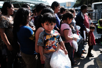 Dozens of women, men and their children, many fleeing poverty and violence in Honduras, Guatamala and El Salvador, arrive at a bus station following release from Customs and Border Protection on June 23 in McAllen, Texas. Photo by Spencer Platt/Getty Images
