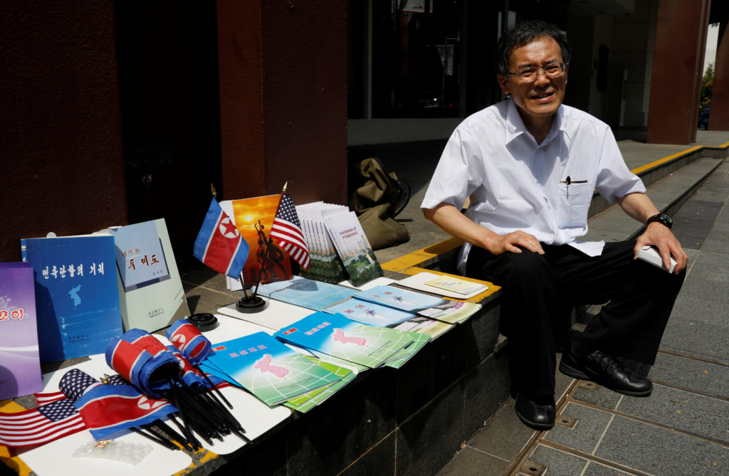 Jun Miyagawa, a Japanese speciality bookdealer on North Korea publications, sits next to North Korean publications he is displaying next to St. Regis hotel in Singapore June 11, 2018.  REUTERS/Tyrone Siu 