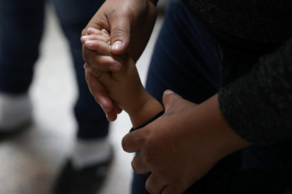 A woman holds a child's hand as undocumented immigrant families are released from detention at a bus depot in McAllen, Texas. Photo by Loren Elliott/Reuters