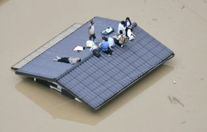 An aerial view shows local residents seen on the roof of submerged house at a flooded area as they wait for a rescue in Kurashiki, southern Japan, in this photo taken by Kyodo. Photo by Kyodo via Reuters