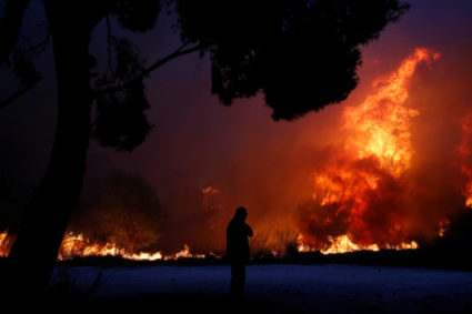 A man looks at the flames as a wildfire burns in the town of Rafina, near Athens, Greece. Photo by Costas Baltas/Reuters