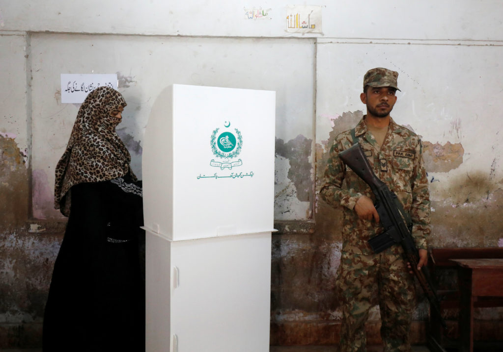 A woman votes next to a soldier at a polling station during the general election in Karachi, Pakistan, on July 25. Photo by Akhtar Soomro/Reuters
