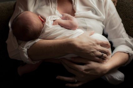 Mother holding newborn baby in arms. Photo by Getty Images.