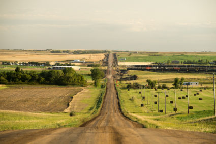 A view south on 93rd Ave., NW towards Hwy 2, a train hauling oil tank cars can be seen at right near Manitou, M.T., Sept 14, 2013. The train will soon be delivering crude oil to refineries in other parts of the state. Back in 2008 the North Dakota oil boom started its ongoing period of extraction of oil from the Bakken formation. The amount of jobs the oil boom has provided North Dakota has helped give it the lowest unemployment rate in the United States and and gave it a billion dollar surplus (Photo by Ken Cedeno/Corbis via Getty Images)
