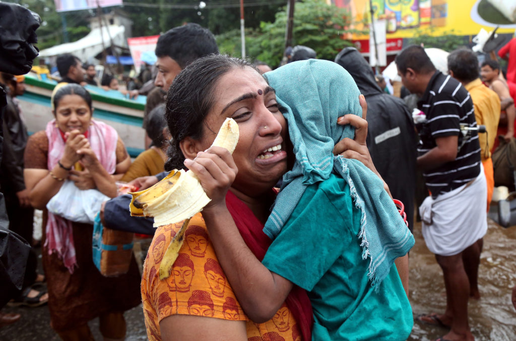 A woman cries as she holds her son after they were evacuated from a flooded area in Aluva in the southern state of Kerala,...