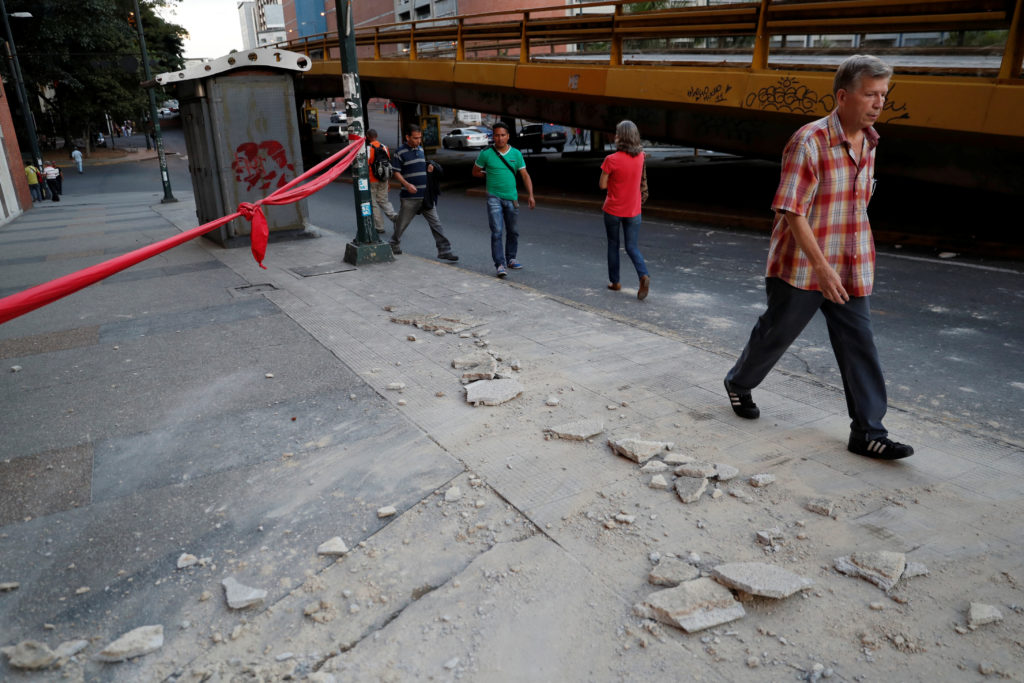 People walk near debris after an earthquake struck the northern coast of Venezuela, in Caracas. Photo by Carlos Garcia Rawlins/Reuters