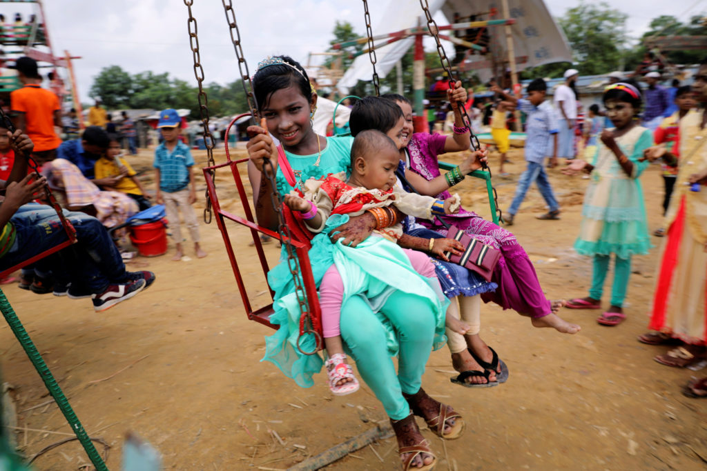 Rohingya refugee children take a swing ride on the holiday Eid al-Adha in the Kutupalong refugee camp in Cox's Bazar, Bang...