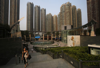 A woman walks up the stairs as luxurious high rise residential buildings in Hong Kong's West Kowloon district. It would take 22 years worth of an average Hong Kong salary to by a 60-square meter apartment there. Photo by Bobby Yip/Reuters