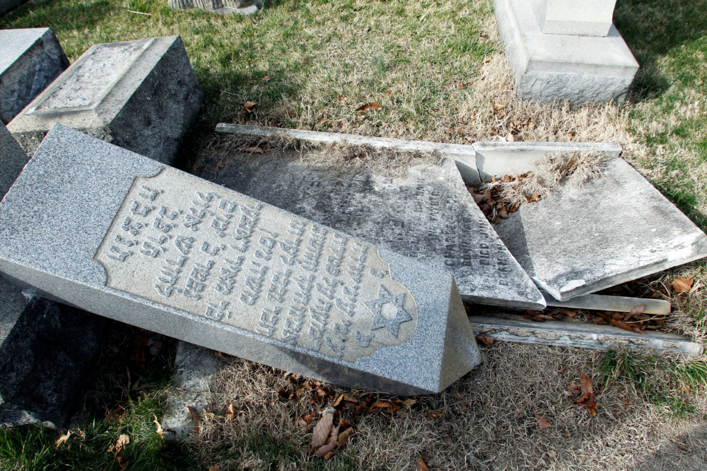 A headstone, pushed off its base by vandals, lays on the ground near a smashed tomb in the Mount Carmel Cemetery, a Jewish...