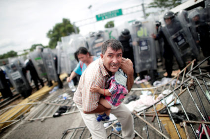 A Honduran migrant protects his child after fellow migrants, part of a caravan trying to reach the U.S., stormed a border checkpoint in Guatemala, in Ciudad Hidalgo, Mexico October 19, 2018. Photo by REUTERS/Ueslei Marcelino