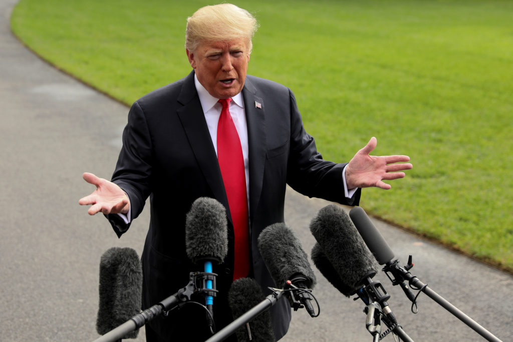 U.S. President Donald Trump answers a question as he talks to reporters while heading to the Marine One helicopter to depa...