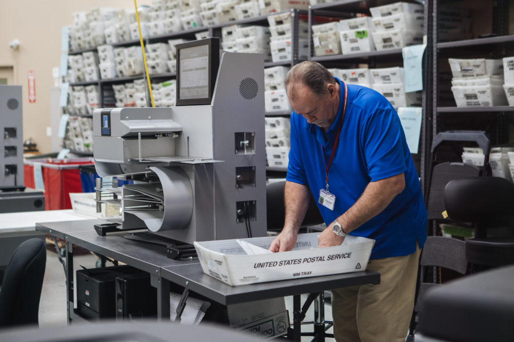 An election worker takes a ballot to place into an electronic counting machine during a recount at the Broward County Supe...