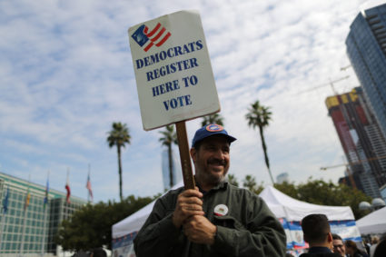 A Democratic Party worker holds up a sign encouraging immigrants who have become new U.S. citizens to sign up to vote in the upcoming midterm elections outside a naturalization ceremony in Los Angeles, California. Photo by Lucy Nicholson/Reuters