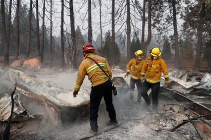 Firefighters move debris while recovering human remains from a trailer home destroyed by the Camp Fire in Paradise, California, U.S., November 17, 2018. Photo by Terray Sylvester/Reuters