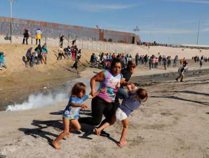 A migrant family, part of a caravan of thousands traveling from Central America en route to the United States, run away from tear gas in front of the border wall between the U.S and Mexico in Tijuana, Mexico November 25, 2018. Photo by Kim Kyung/Reuters